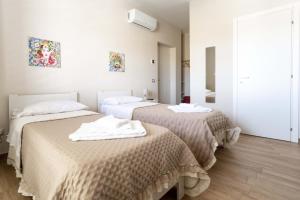 2 łóżka w pokoju z białymi ścianami i drewnianą podłogą w obiekcie B&B Ercole Agrigento w mieście Villaggio Mosè