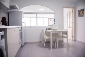 una cocina con una mesa y sillas blancas y una ventana en SUNSET HOME wifi, en Los Realejos