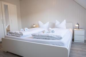 Una cama blanca con sábanas blancas y toallas. en Ferienwohnung-Haus-Ingeborg-Wohnung-3-OG, en Cuxhaven