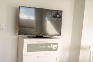 telewizor z płaskim ekranem siedzący na białej komodzie w obiekcie Ferienwohnung-Haus-Ingeborg-Wohnung-3-OG w mieście Cuxhaven