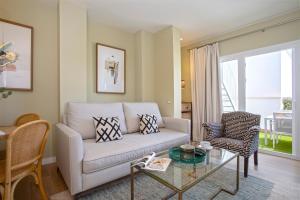 un soggiorno con divano e tavolo in vetro di Genteel Home Castilla Terrace a Siviglia