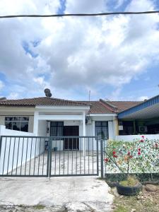 a white house with a gate and flowers at Cozy 18 Entire 3 Bedroom @Alma Bukit Mertajam in Bukit Mertajam