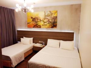 a hotel room with two beds and a painting on the wall at Raintree Boutique Hotel in Kajang