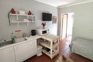 a kitchen with a desk with a microwave and a bed at Garden cottage in Cape Town