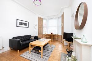 a living room with a black couch and a table at ALTIDO Charming 1-bed ap near Leith Links w/ patio in Edinburgh