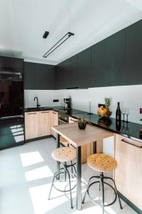 una cocina con armarios negros, mesa de madera y taburetes en Andromahi Apartments & Suite, en Laganas