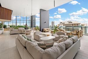 a living room with a couch and tables and chairs at Lamour Ocean View Apartment I in Casino Broadbeach - free parking in Gold Coast