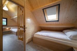 2 Betten in einer Holzhütte mit Fenster in der Unterkunft PLAŻOWY ZAKĄTEK in Lubrza