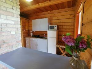 a kitchen in a log cabin with a table and flowers at Sodyba "Vytauto kaimas" Aukštadvaris in Aukštadvaris +14 photos