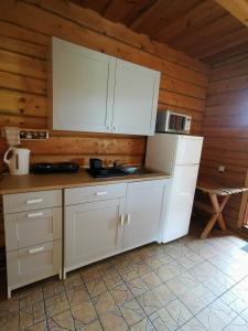 a kitchen with white cabinets in a wooden room at Sodyba "Vytauto kaimas" Aukštadvaris in Aukštadvaris
