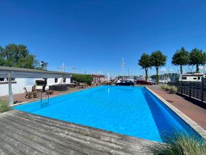 RönnauHausboot mit Traumlage in Lübeck-Travemünde的码头旁的大型蓝色游泳池