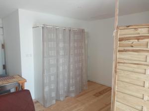 um quarto com cortinas brancas e piso de madeira em L’Oiseau rêveur em Darbres