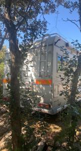 uma caravana está estacionada ao lado de uma árvore em Camping car fixe dans la campagne em Pianottoli-Caldarello