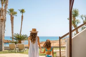 a woman and a little girl walking down the stairs to the beach at Louis Althea Beach in Protaras
