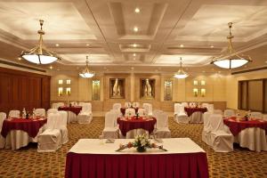 a banquet hall with tables and white chairs and lights at The Bristol in Gurgaon
