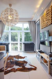 a living room with a large window and a chandelier at Apartament Royal Centrum in Krynica Zdrój