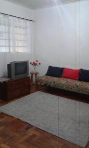 a living room with a couch and a tv at Casa para temporada in Serra Negra