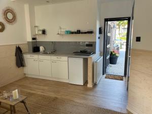 a kitchen with white cabinets and a door leading to a patio at Studio 41 Bergen NH in Bergen