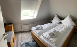 Schlafzimmer mit einem Bett mit weißer Bettwäsche und einem Fenster in der Unterkunft Oasis 07 in Cuxhaven