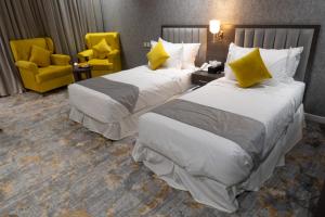 فندق دبليو اس ws في تبوك: سريرين في غرفة الفندق مع كراسي صفراء