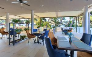 a restaurant with tables and chairs and windows at Hotel Bor in Krk