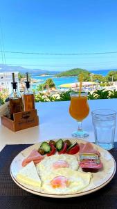 a plate of eggs and vegetables on a table with a drink at Hotel Ardiani in Ksamil