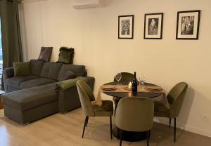 ein Wohnzimmer mit einem Sofa, einem Tisch und Stühlen in der Unterkunft Charmant T2 proche de la plage et au calme in Ajaccio