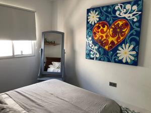 een slaapkamer met een schilderij van een hart aan de muur bij ABA DALÍ in Conil de la Frontera