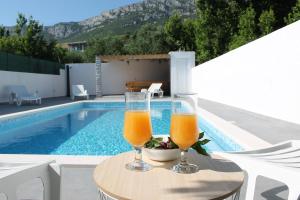 2 vasos de zumo de naranja en una mesa junto a la piscina en "Heaven on earth" with pool, en Kaštel Sućurac