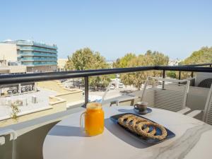 a table with a glass of orange juice on a balcony at The H Experience Boutique Apartment Downtown Heraklion in Heraklio