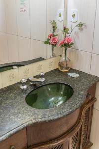 a bathroom with a green sink and a mirror at Pousada dos Sinos in São João del Rei