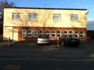 two cars parked in a parking lot in front of a building at Hillingdon Lodge in Hillingdon