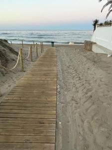 a wooden boardwalk on the beach next to the ocean at Casa Holandaluzas Marbella near Beach, with salt water Pool and private parking in Marbella