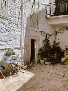 Un patio con una mesa y plantas en macetas al lado de un edificio. en Casa Nené, en Cisternino