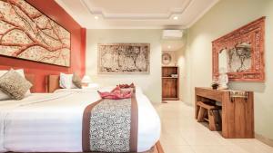 a bedroom with a large bed and a desk at The Village Guest House in Ubud