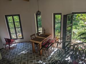 una mesa y sillas en una habitación con ventanas en La Molina - casas independientes en naturaleza excepcional en Setenil