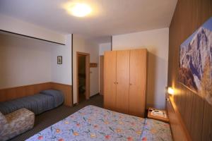 a hotel room with a bed and a cabinet at Hotel Miramonti in Vigo di Fassa