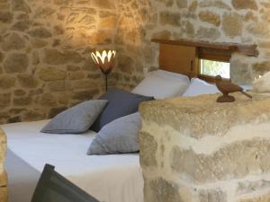 a bedroom with a bed with a stone wall at Le Hameau du Quercy in Frontenac