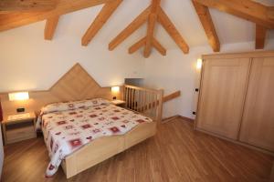 1 dormitorio con 1 cama y suelo de madera en Hotel Miramonti, en Vigo di Fassa