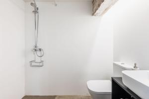 a white bathroom with a toilet and a sink at La Casa Baja in Sagunto