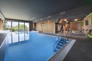 a large swimming pool with a staircase in a building at Chateau Loucen Garden Retreat in Loučeň