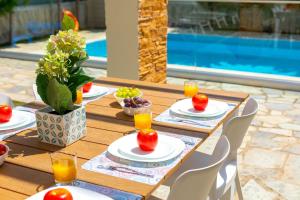 einem Holztisch mit Teller mit Lebensmitteln und Orangensaft in der Unterkunft Ayia Napa Ionion Seaside Villa in Ayia Napa