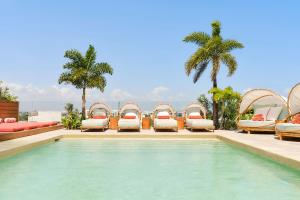 a pool with chaise lounge chairs and a resort at CALIXTA Hotel in Playa del Carmen