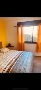 a bedroom with a bed and a window with orange curtains at Les villas du cap piscine chauffée avril à octobre in Saint-Joseph