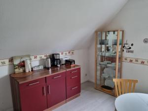 a kitchen with red cabinets and a glass shelf at Unterkunft in Erholungsort Sterup Nähe von Ostsee in Sterup
