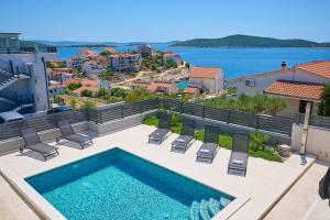 una piscina con sillas y vistas al agua en Luxury Villa Mia - Sevid en Sevid
