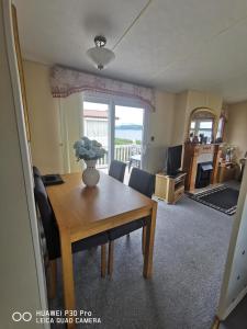 a dining room with a table and chairs and a window at Oor wee hoose in Leswalt