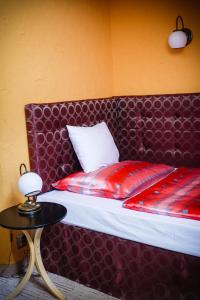 a bed with a red head board and a table at Penzion Tilia in Levice