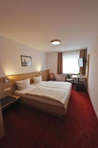 フロイデンシュタットにあるHotel Gasthof Jägerstübleの大きなベッドとデスクが備わるホテルルームです。