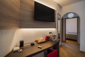 a hotel room with a desk with a television on the wall at Your lovely and elegant home with garden sea view in La Maddalena